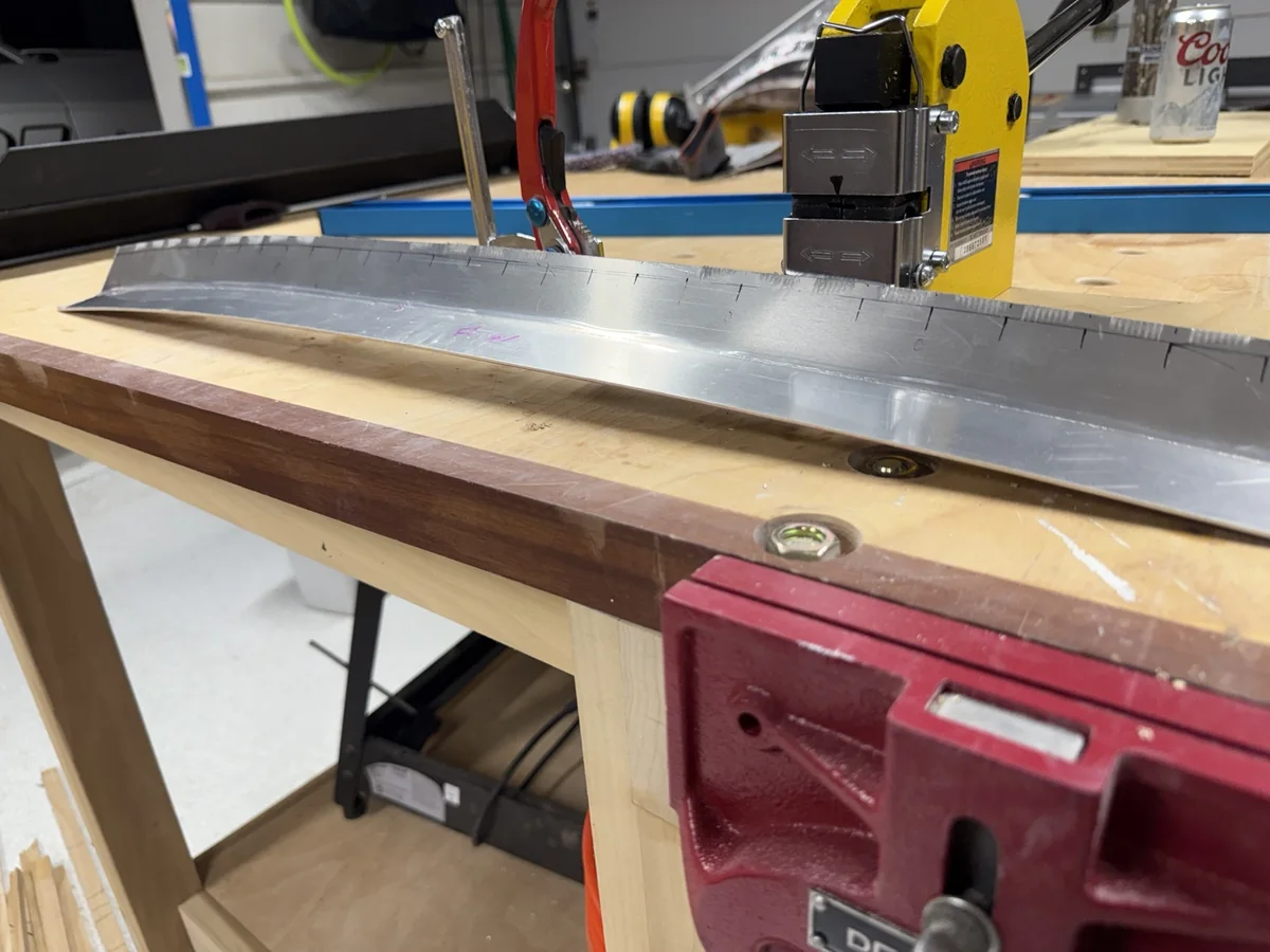 Aluminum gurney flap with a developing curve and stretcher jaw marks along its upper edge.