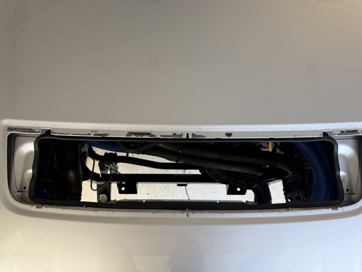 Enlarged GT500 hood-vent opening with black rubber trim fitted around the cut aluminum edge.