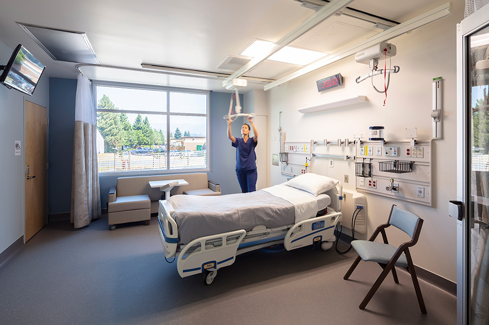 Adventist Health UVMC Ukiah Valley ED Expansion & ICU Addition, Ukiah, CA: Healthcare renovation, tenant improvement and new construction by Herrero Builders in an occupied environment, with Lionakis. Interior view of a hospital patient room with a bed, window and ceiling lift.
