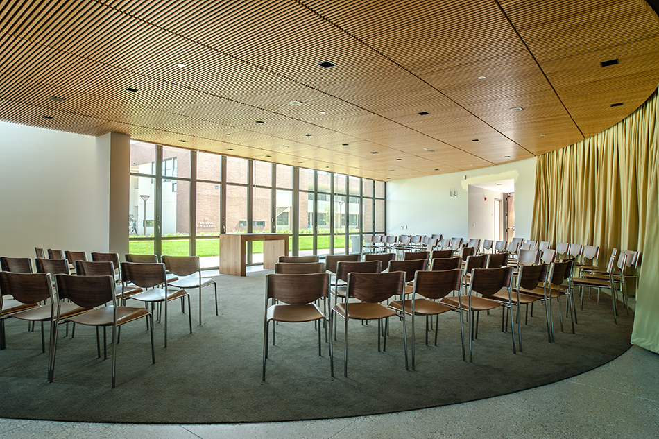 Sacred Heart Schools Atherton Lower & Middle School, Atherton, CA: Education new construction by Herrero Builders on a LEED Gold net zero energy campus, with WRNS Studio. Interior view of a curved assembly room with a wood slat ceiling, a gold curtain and rows of chairs facing the windows.