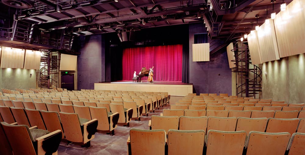 University High School Student Center, Upper & Lower Campuses, Ross, CA: Education New Construction and Renovation by Herrero Builders with historic preservation, with SMWM, Studio Bondy. Interior view of a performance hall with a red stage curtain and two musicians on stage.