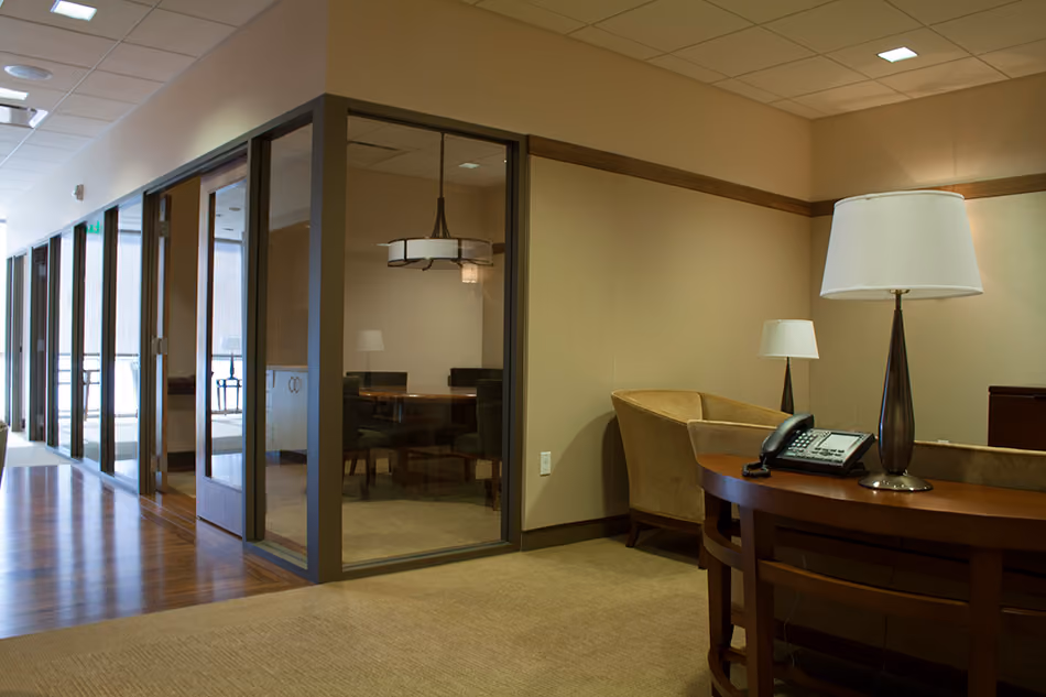 Sutter Health PAMF Burlingame Medical Office Building, Burlingame, CA: Healthcare Tenant Improvements by Herrero Builders under Integrated Project Delivery, with Hawley Peterson Snyder. Interior view of a corridor with a glass-walled meeting room, wood floor and a table lamp in the foreground.