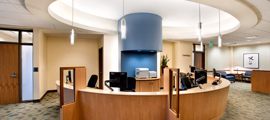 Sutter Health PAMF Burlingame Medical Office Building, Burlingame, CA: Healthcare Tenant Improvements by Herrero Builders under Integrated Project Delivery, with Hawley Peterson Snyder. Interior view of a circular reception station with a blue column and a curved ceiling soffit.