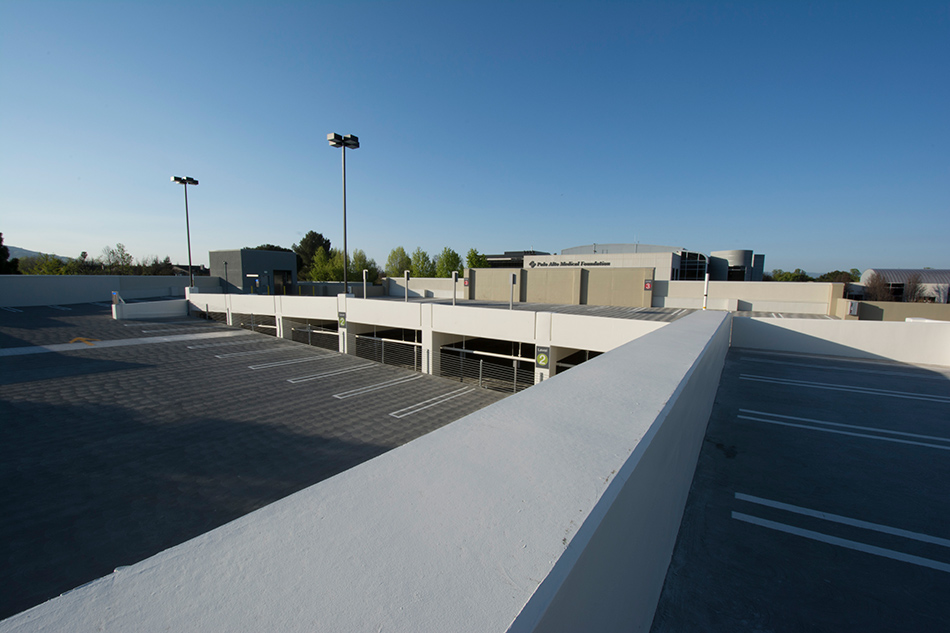 Sutter Health PAMF Fremont Ambulatory Surgery Center & Parking Garage, Fremont, CA: Healthcare New Construction by Herrero Builders in an occupied healthcare environment, with Boulder Architects. Site view of the parking structure's upper deck with painted stalls and campus buildings beyond.