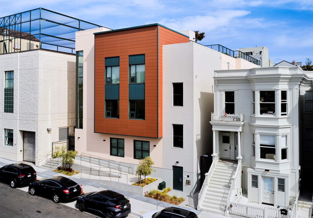 San Francisco Day School School Addition and Staff Housing, San Francisco, CA: Education new construction by Herrero Builders under Integrated Project Delivery, with Studio Bondy. Exterior view of the street-facing addition with an orange panel bay, ramp and stair beside a neighboring house.