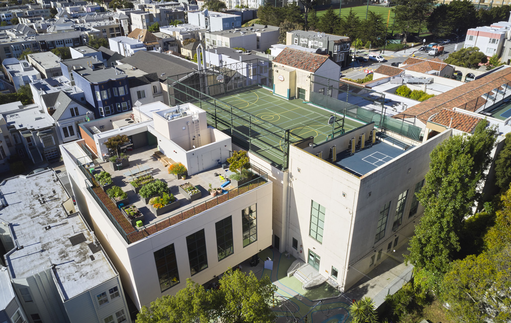 San Francisco Day School School Addition and Staff Housing, San Francisco, CA: Education new construction by Herrero Builders under Integrated Project Delivery, with Studio Bondy. Aerial view of the roof with a green athletic court and terrace seen over surrounding rooftops.