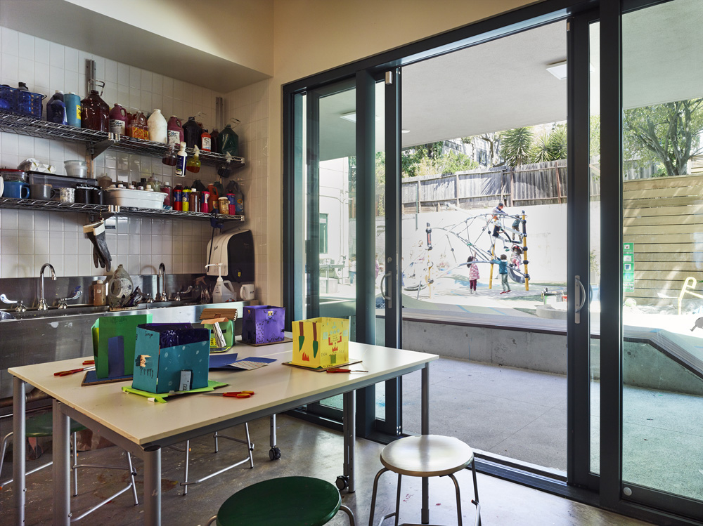 San Francisco Day School School Addition and Staff Housing, San Francisco, CA: Education new construction by Herrero Builders under Integrated Project Delivery, with Studio Bondy. Interior view of an art room with a worktable, shelving of supplies and sliding glass doors to the playground.