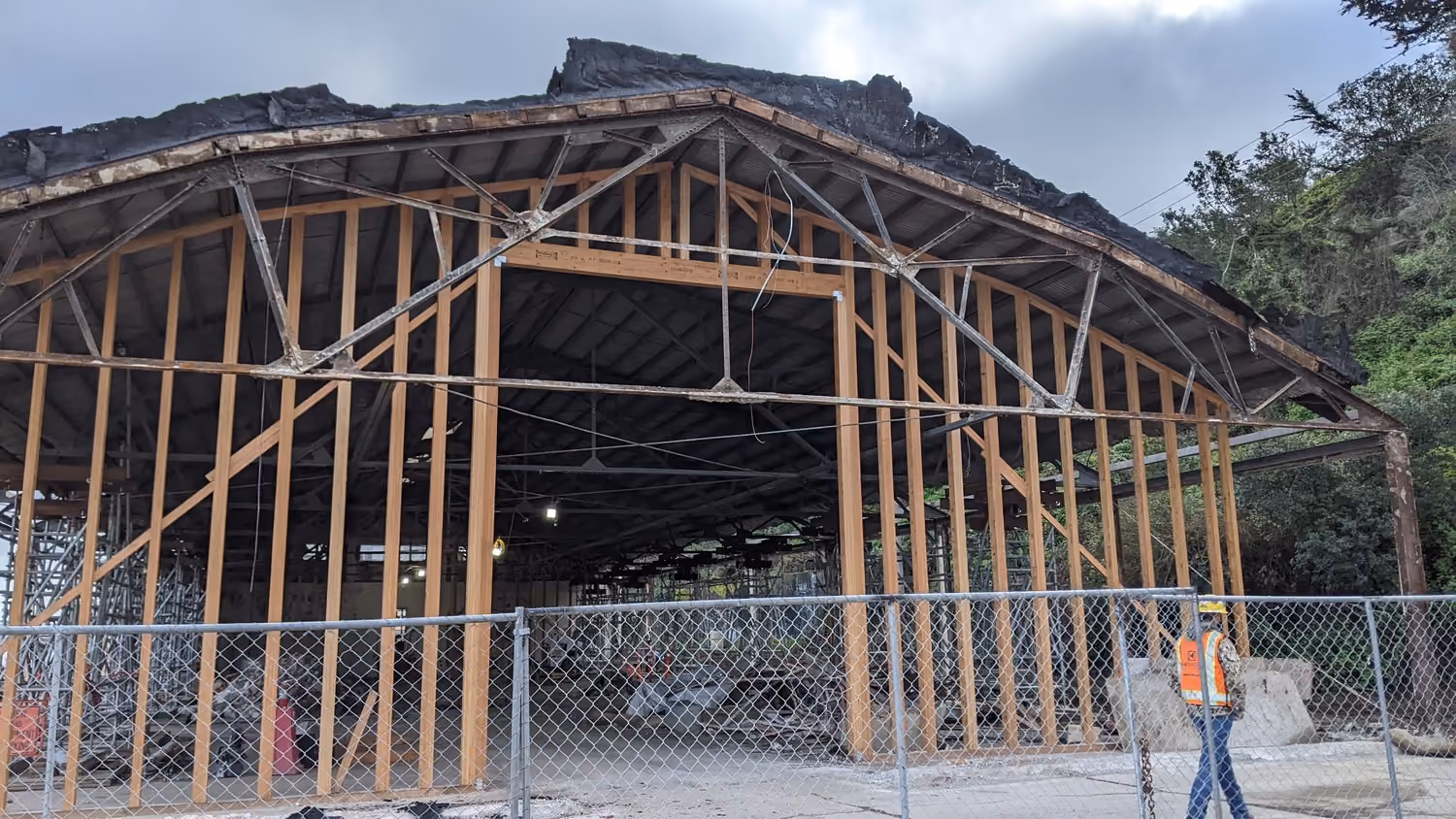 National Park Service Crissy Field Hangar Rehabilitation (Presidio Building 643), San Francisco, CA: Historic renovation by Herrero Builders using Lean construction, with Siegel & Strain Architects. Construction-phase view of exposed timber wall framing and roof structure behind fencing.