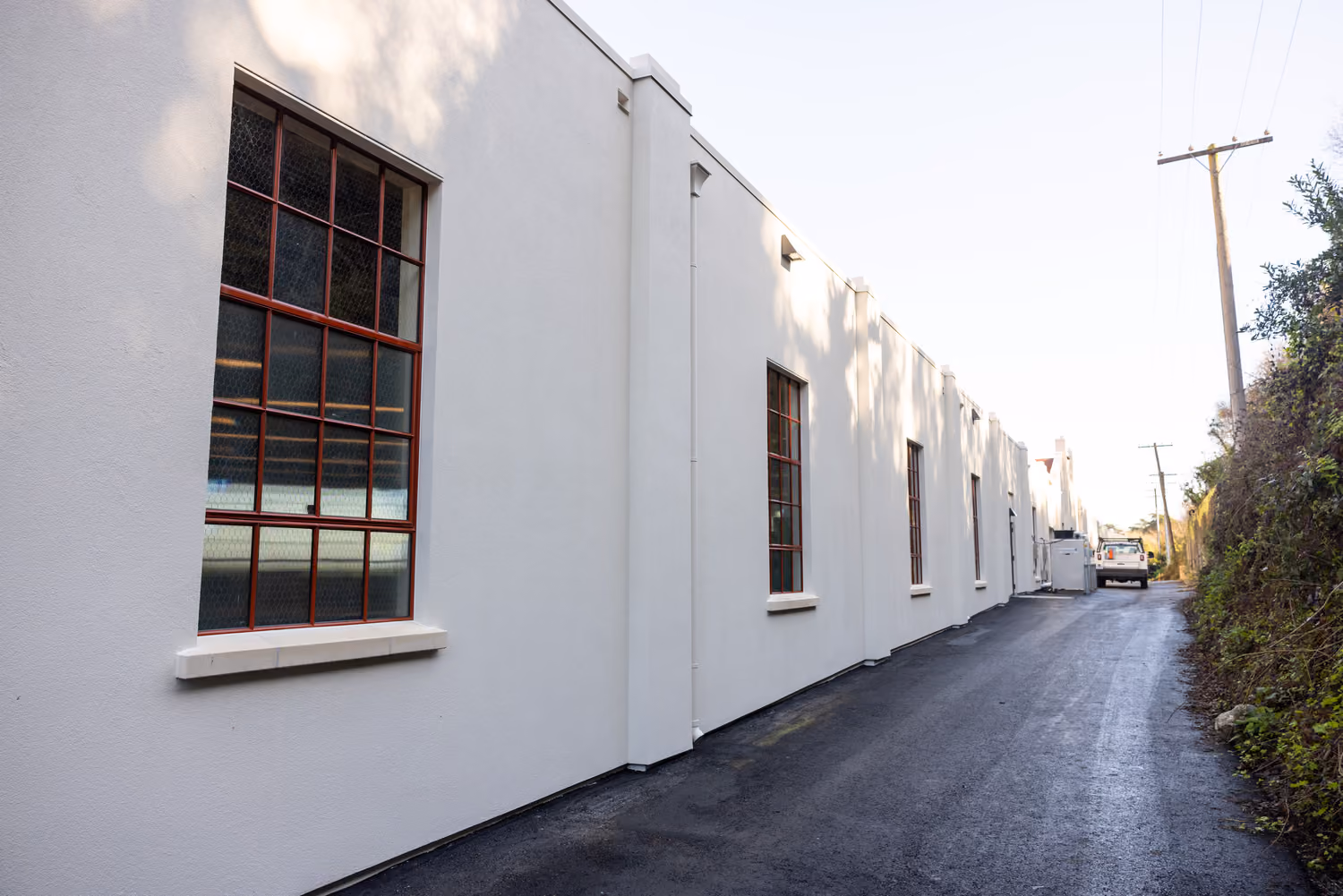 National Park Service Crissy Field Hangar Rehabilitation (Presidio Building 643), San Francisco, CA: Historic renovation by Herrero Builders using Lean construction, with Siegel & Strain Architects. Exterior view of the white stucco side elevation with red-framed multi-pane windows.