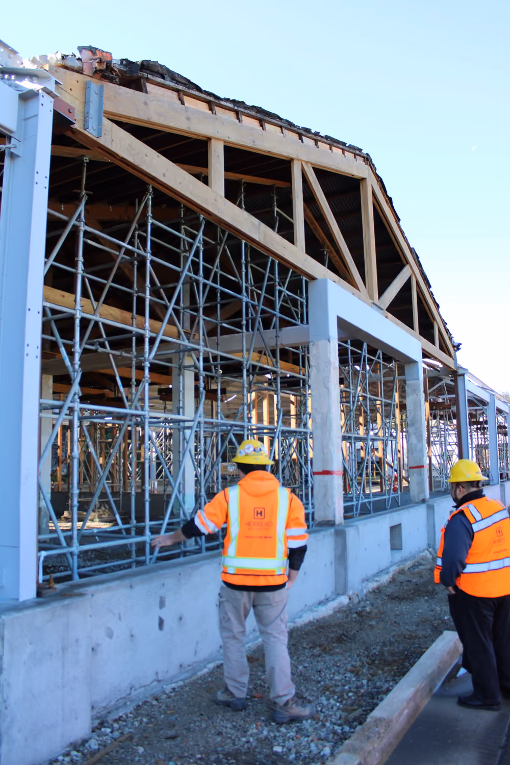 National Park Service Crissy Field Hangar Rehabilitation (Presidio Building 643), San Francisco, CA: Historic renovation by Herrero Builders using Lean construction, with Siegel & Strain Architects. Construction-phase view of scaffolding inside a concrete and steel frame with workers in vests.