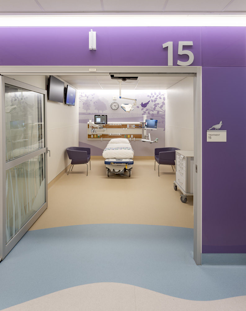 Stanford Health Care Stanford Health Pediatric Emergency Department, Palo Alto, CA: Healthcare renovation by Herrero Builders in an occupied hospital, with Ratcliff. Interior view of an exam room entrance with a purple header, number 15, a bed and two chairs.