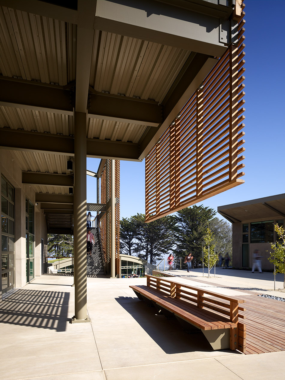 Nueva School Hillside Learning Complex & Historic Crocker Mansion, Hillsborough, CA: Education and Historic new construction and renovation by Herrero Builders earning LEED Gold, with Leddy Maytum Stacy Architects. Detail of a covered walkway with a timber screen and slatted bench.