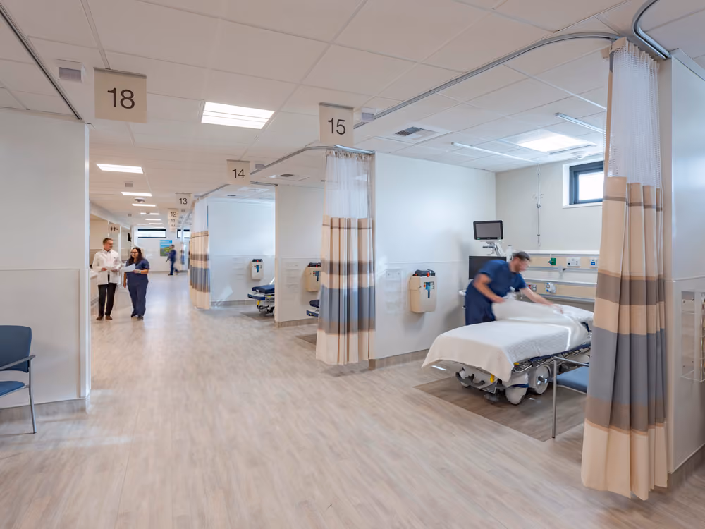 Sutter Health Santa Rosa Regional Hospital Expansion, Santa Rosa, CA: Healthcare New Construction by Herrero Builders under Integrated Project Delivery with Lean construction, with Stantec. Interior view of a corridor of numbered patient bays with striped privacy curtains.