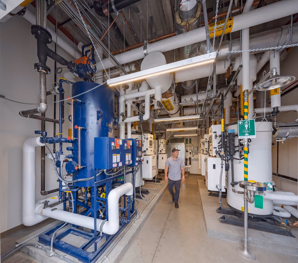 Sutter Health Santa Rosa Regional Hospital Expansion, Santa Rosa, CA: Healthcare New Construction by Herrero Builders under Integrated Project Delivery with Lean construction, with Stantec. Interior view of a mechanical room with blue and white tanks and insulated piping overhead.
