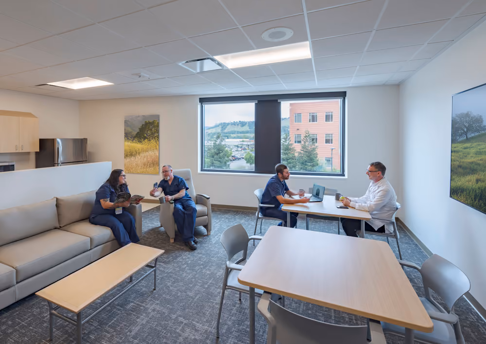 Sutter Health Santa Rosa Regional Hospital Expansion, Santa Rosa, CA: Healthcare New Construction by Herrero Builders under Integrated Project Delivery with Lean construction, with Stantec. Interior view of a staff lounge with a sofa, tables, chairs and landscape artwork.