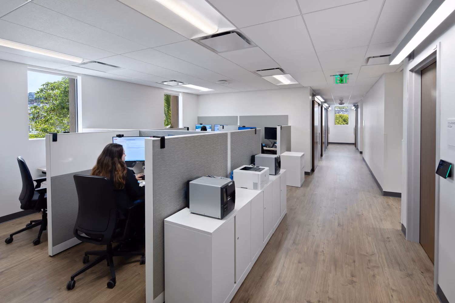 Sutter Health Monteagle Multispecialty Center, San Francisco: Healthcare multi-floor tenant improvement by Herrero Builders occupied during construction, with Polytech Architects and HED. Interior view of an open office area with cubicles, a workstation and a corridor.