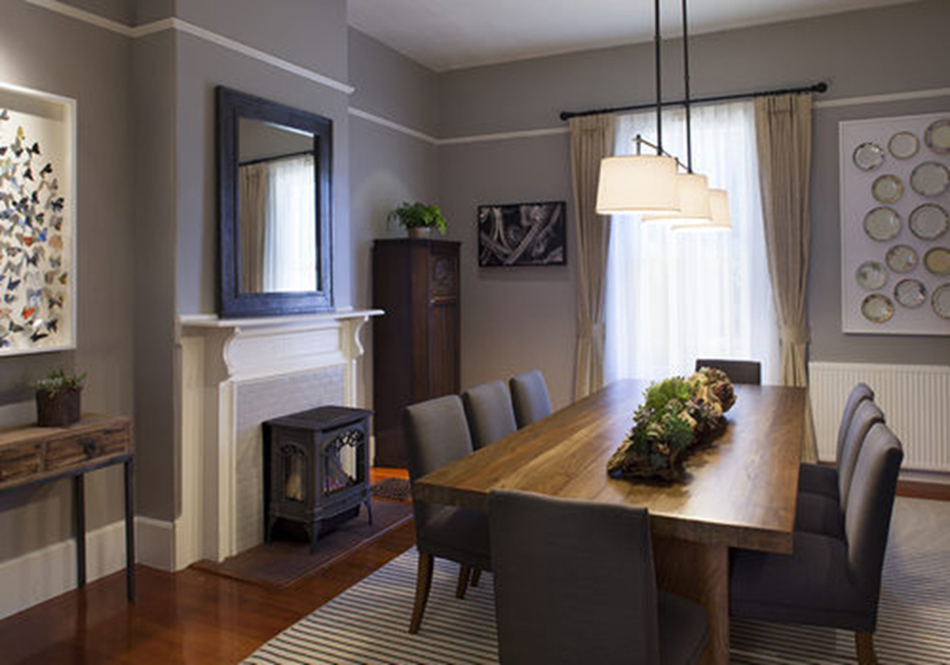 The Presidio Trust Funston House, San Francisco, CA: Hospitality and Historic renovation by Herrero Builders preserving a historic officer's home, with Architectural Resource Group. Interior view of a dining table with gray upholstered chairs beside a fireplace stove.