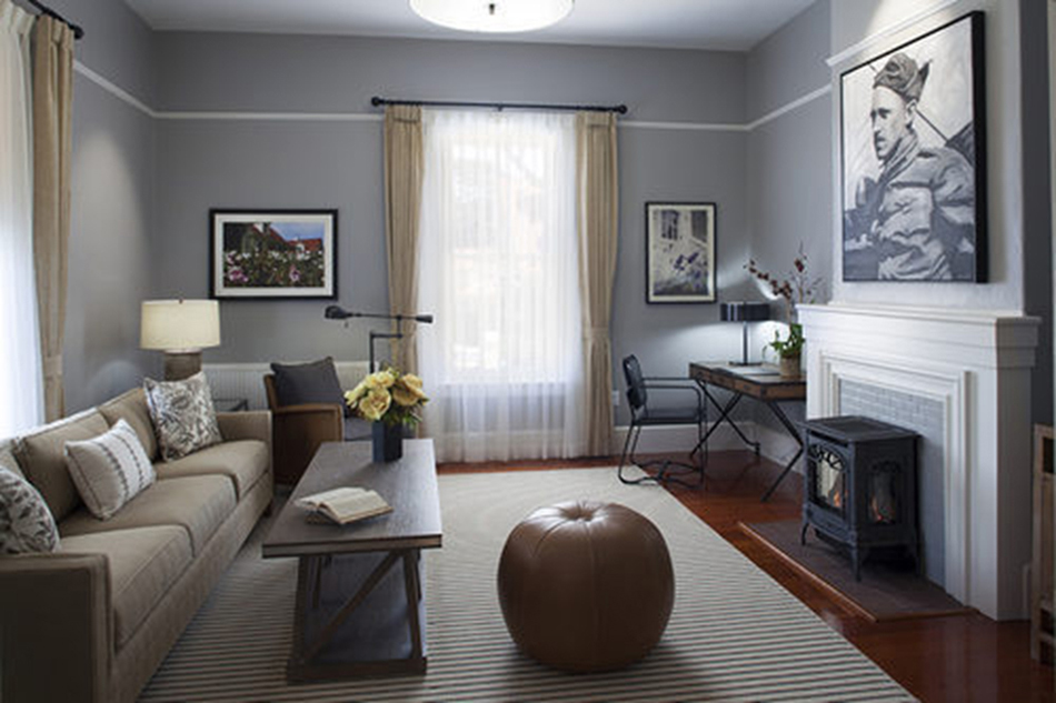 The Presidio Trust Funston House, San Francisco, CA: Hospitality and Historic renovation by Herrero Builders preserving a historic officer's home, with Architectural Resource Group. Interior view of a sitting room with gray walls, a sofa, a leather pouf and a fireplace stove.