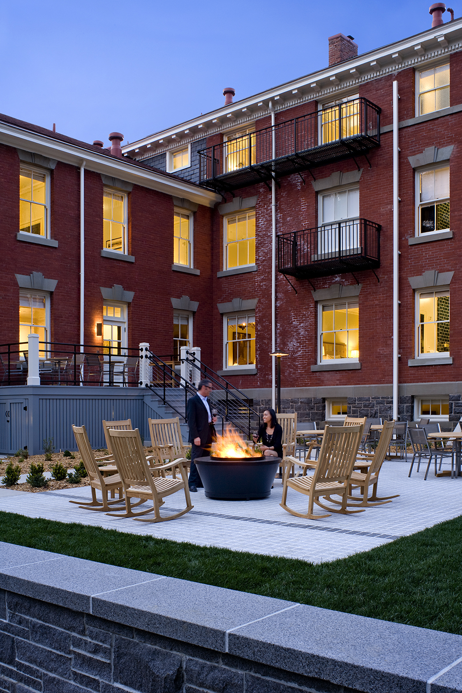 The Presidio Trust Inn at the Presidio, San Francisco, CA: Hospitality and Historic renovation by Herrero Builders preserving a National Historic Landmark, with Architectural Resources Group. Exterior view of the rear brick wing with iron balconies and a patio with rocking chairs around a fire pit.