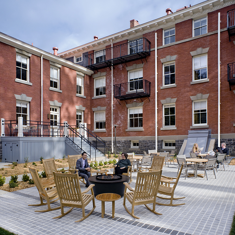 The Presidio Trust Inn at the Presidio, San Francisco, CA: Hospitality and Historic renovation by Herrero Builders preserving a National Historic Landmark, with Architectural Resources Group. Exterior view of a courtyard patio with rocking chairs, a fire pit and seating beside exterior stairs.
