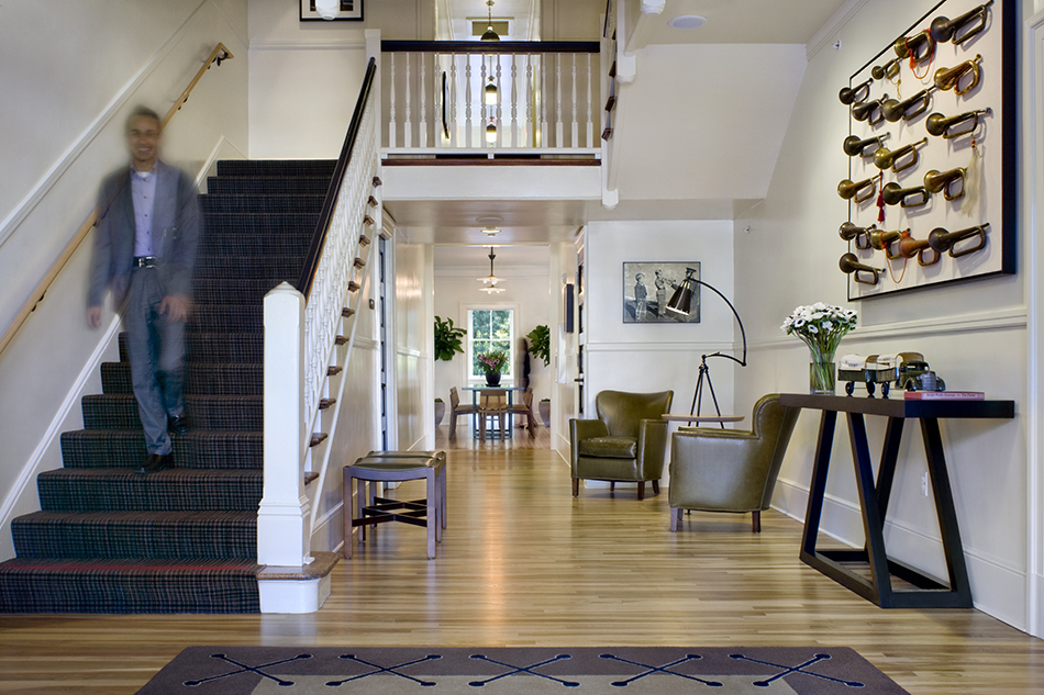 The Presidio Trust Inn at the Presidio, San Francisco, CA: Hospitality and Historic renovation by Herrero Builders preserving a National Historic Landmark, with Architectural Resources Group. Interior view of the entry hall with a staircase, a bugle wall display and a hardwood floor.