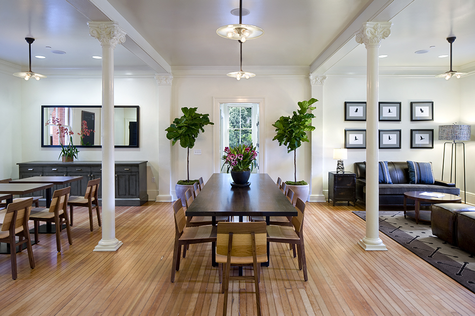The Presidio Trust Inn at the Presidio, San Francisco, CA: Hospitality and Historic renovation by Herrero Builders preserving a National Historic Landmark, with Architectural Resources Group. Interior view of a dining and lounge room with white columns and a long wooden table.