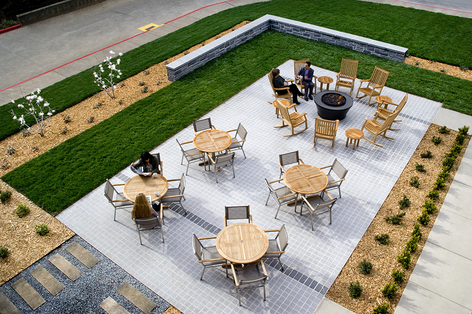 The Presidio Trust Inn at the Presidio, San Francisco, CA: Hospitality and Historic renovation by Herrero Builders preserving a National Historic Landmark, with Architectural Resources Group. Aerial view of a tiled patio with round tables, rocking chairs and a stone wall.