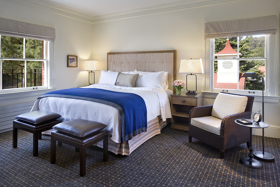 The Presidio Trust Inn at the Presidio, San Francisco, CA: Hospitality and Historic renovation by Herrero Builders preserving a National Historic Landmark, with Architectural Resources Group. Interior view of a guest bedroom with an upholstered headboard, blue throw and a wicker armchair.