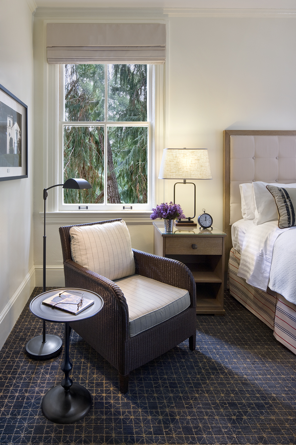 The Presidio Trust Inn at the Presidio, San Francisco, CA: Hospitality and Historic renovation by Herrero Builders preserving a National Historic Landmark, with Architectural Resources Group. Detail of a wicker armchair, side table and reading lamp beside a bedroom window.