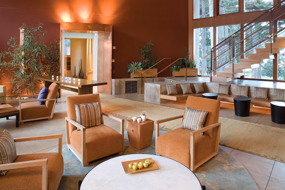 Fort Baker Retreat Group Cavallo Point Lodge & Spa, Sausalito, CA: Hospitality renovation and new construction by Herrero Builders in a historic landmark, with Leddy Maytum Stacy Architectural Resources Group. Interior view of a lounge with orange armchairs, bamboo plants and a stair.
