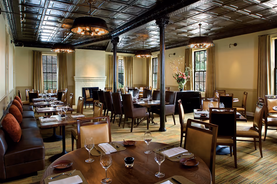 Fort Baker Retreat Group Cavallo Point Lodge & Spa, Sausalito, CA: Hospitality renovation and new construction by Herrero Builders in a historic landmark, with Leddy Maytum Stacy Architectural Resources Group. Interior view of a dining room with a pressed-tin ceiling and wheel-shaped pendants.