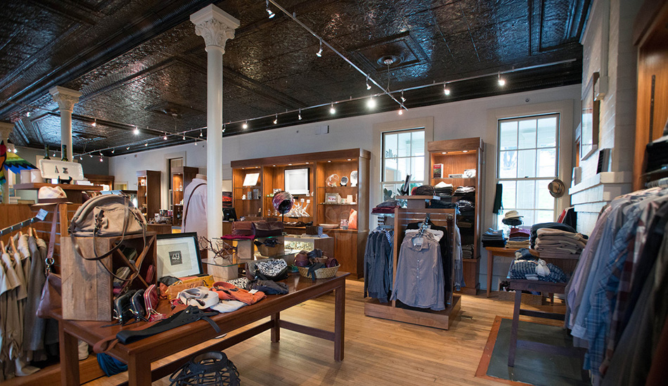 Fort Baker Retreat Group, LLC Mercantile at Cavallo Point, Gift Shop, Sausalito, CA: Commercial & Retail renovation and new construction by Herrero Builders in a historic landmark, with Leddy Maytum Stacy Architects. Interior view of handbags on a wood table and clothing racks.
