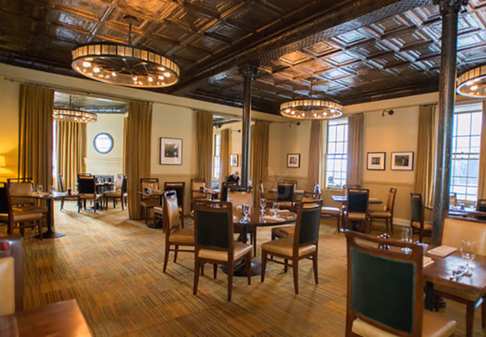 Fort Baker Retreat Group Murray Circle Restaurant, Sausalito, CA: Hospitality and Historic renovation and new construction by Herrero Builders, with Leddy Maytum Stacy Architects. Interior view of the dining room with a pressed-tin ceiling and wagon-wheel pendant lights.