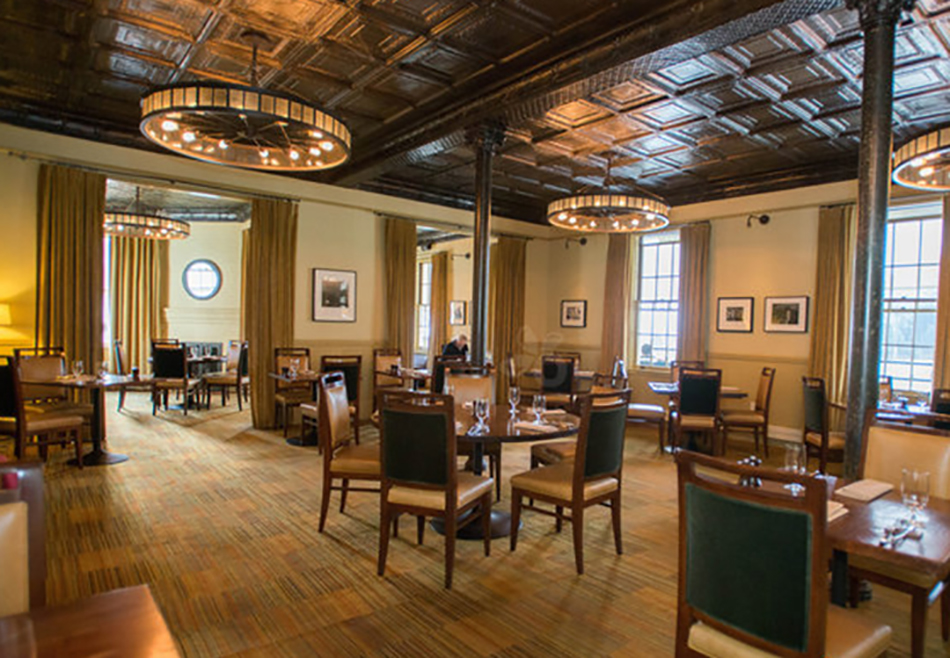 Fort Baker Retreat Group Murray Circle Restaurant, Sausalito, CA: Hospitality and Historic renovation and new construction by Herrero Builders, with Leddy Maytum Stacy Architects. Interior view of the dining room with a pressed-tin ceiling and wagon-wheel pendant lights.
