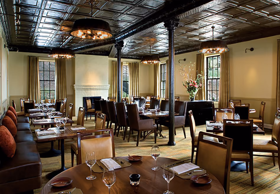Fort Baker Retreat Group Murray Circle Restaurant, Sausalito, CA: Hospitality and Historic renovation and new construction by Herrero Builders, with Leddy Maytum Stacy Architects. Interior view of a dining room with round tables and a leather banquette.