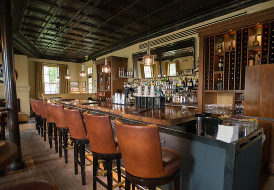 Fort Baker Retreat Group Murray Circle Restaurant, Sausalito, CA: Hospitality and Historic renovation and new construction by Herrero Builders, with Leddy Maytum Stacy Architects. Interior view of the bar with leather stools and a back bar of bottles.