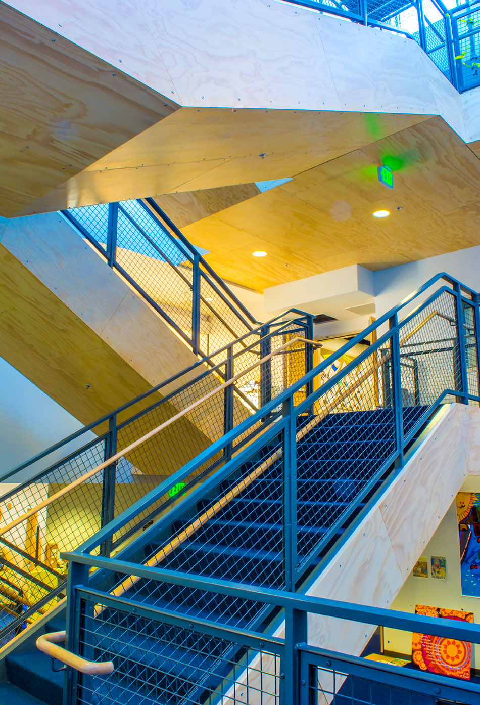 Town School for Boys Core Building & West Wing Excavation, San Francisco, CA: Education New Construction by Herrero Builders with significant excavation on an occupied campus, with MKThink. Interior view of a steel stair with blue railings and wood-clad soffits in the atrium.