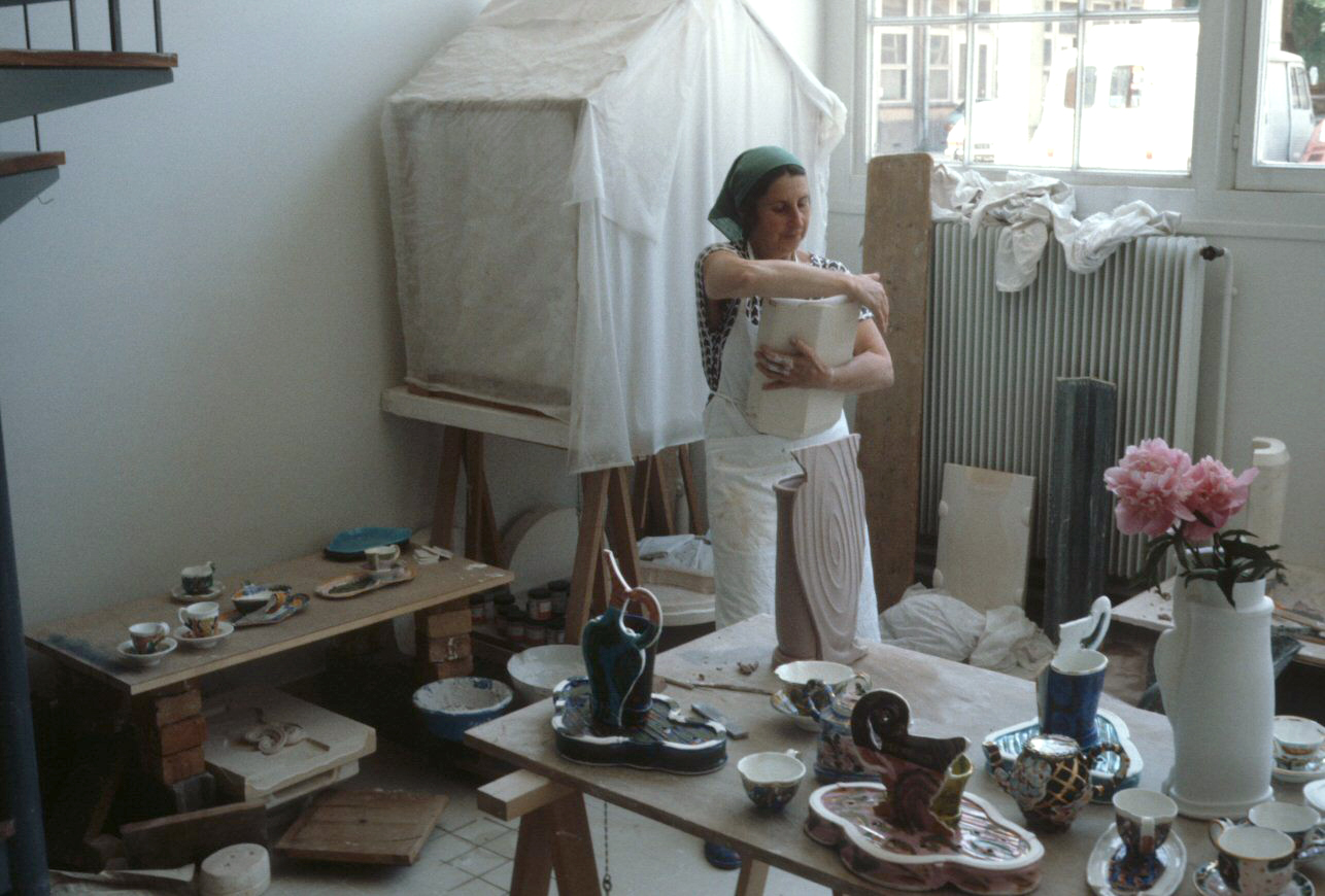 L to R: Betty Woodman working at the Manufacture nationale de Sèvres, France, c. 1987 / Installation views, Betty Woodman: L’allegra vitalità delle porcellane, Palazzo Pitti, Museo delle Porcelane, Florence, Italy, 2010 / Betty Woodman. Puccini, 1989. 6 x 13.2 x 8.274 in. Glazed porcelain / Betty Woodman. Beccafumi, 2002. 8.9 x 7.9 x 8.2 in. Glazed porcelain © Woodman Family Foundation / Artists Rights Society (ARS), New York