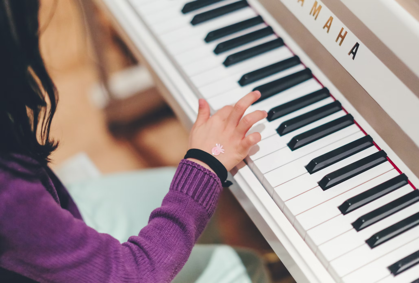 A child playing a piano with a sticker on the back of their hand.