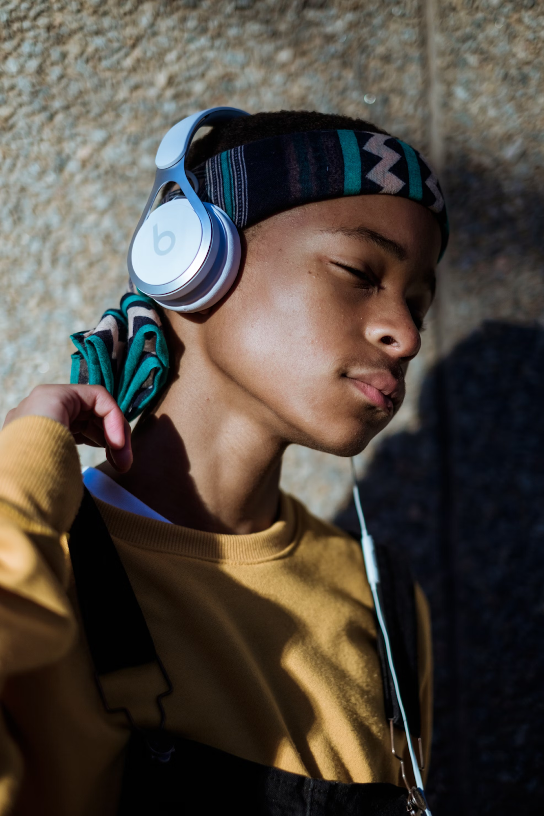 A child wearing headphones, eyes closed, listening to music with a calm expression.