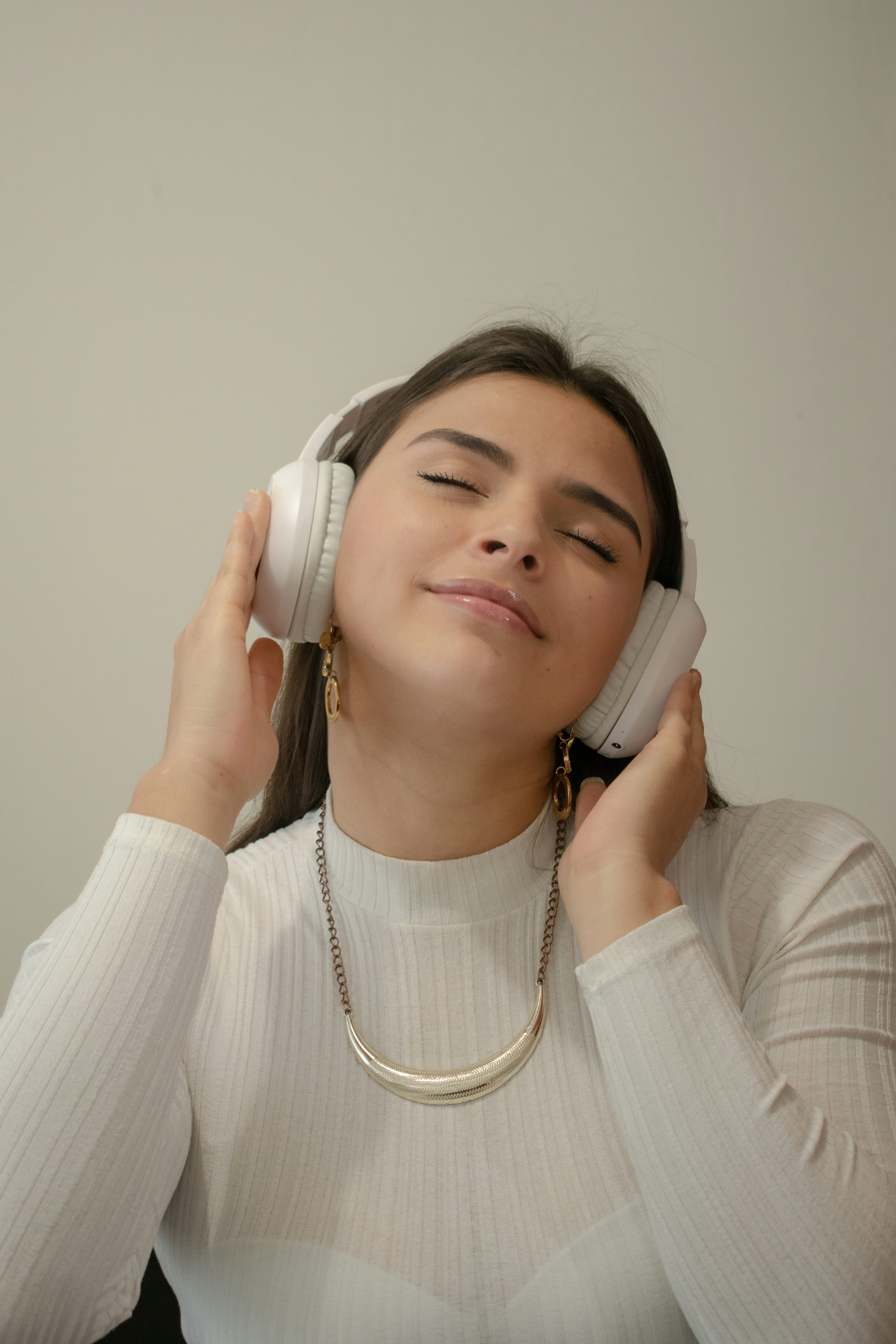 a woman with her eyes closed pressing her headphones into her ears.