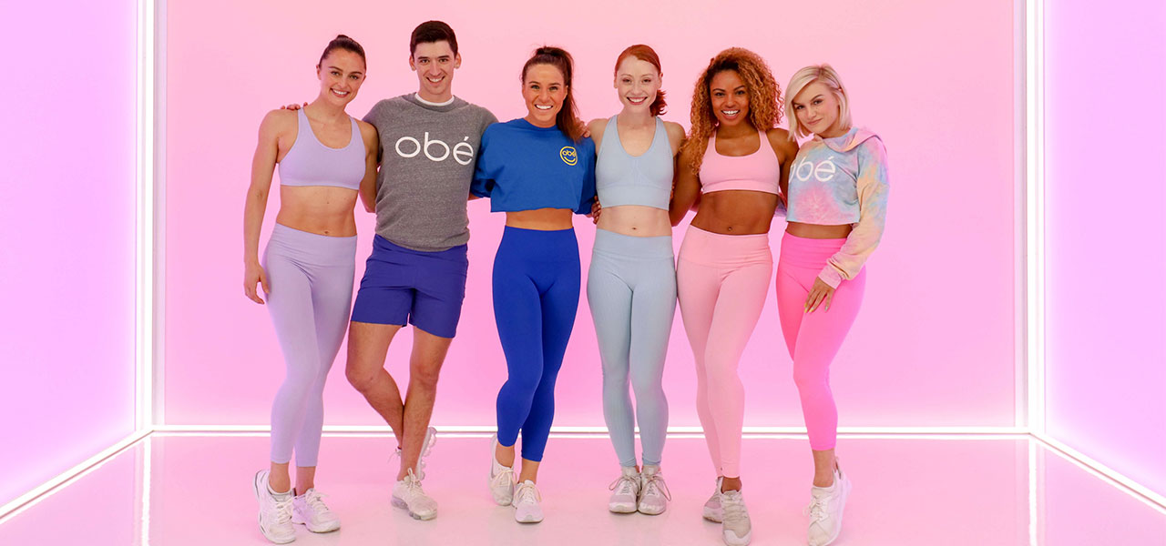 Group shot of Obe fitness trainers in front of a bright pink wall.