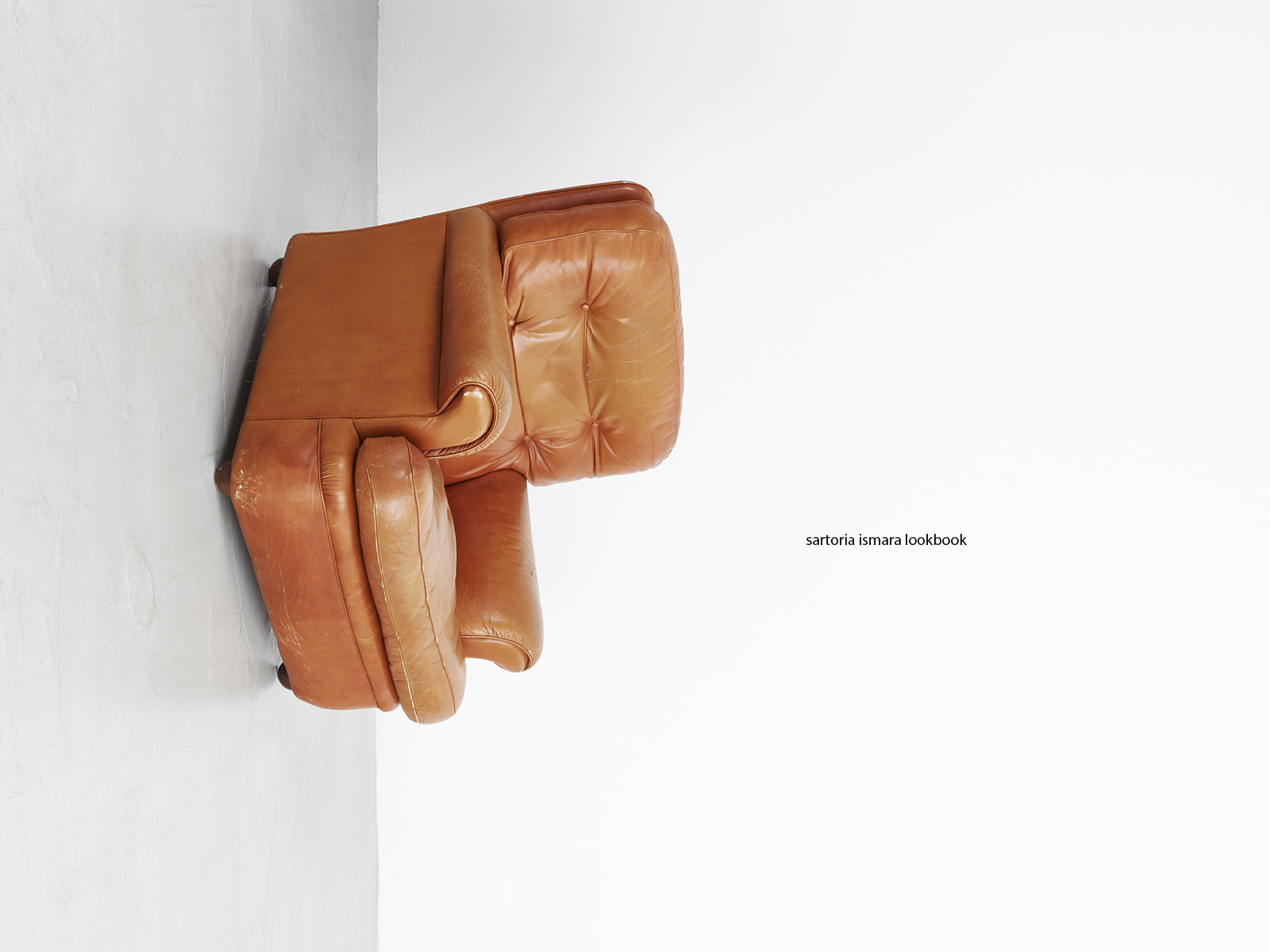 Servizi fotografici professionali per cataloghi moda: poltrona vintage in pelle color cuoio in studio minimal.