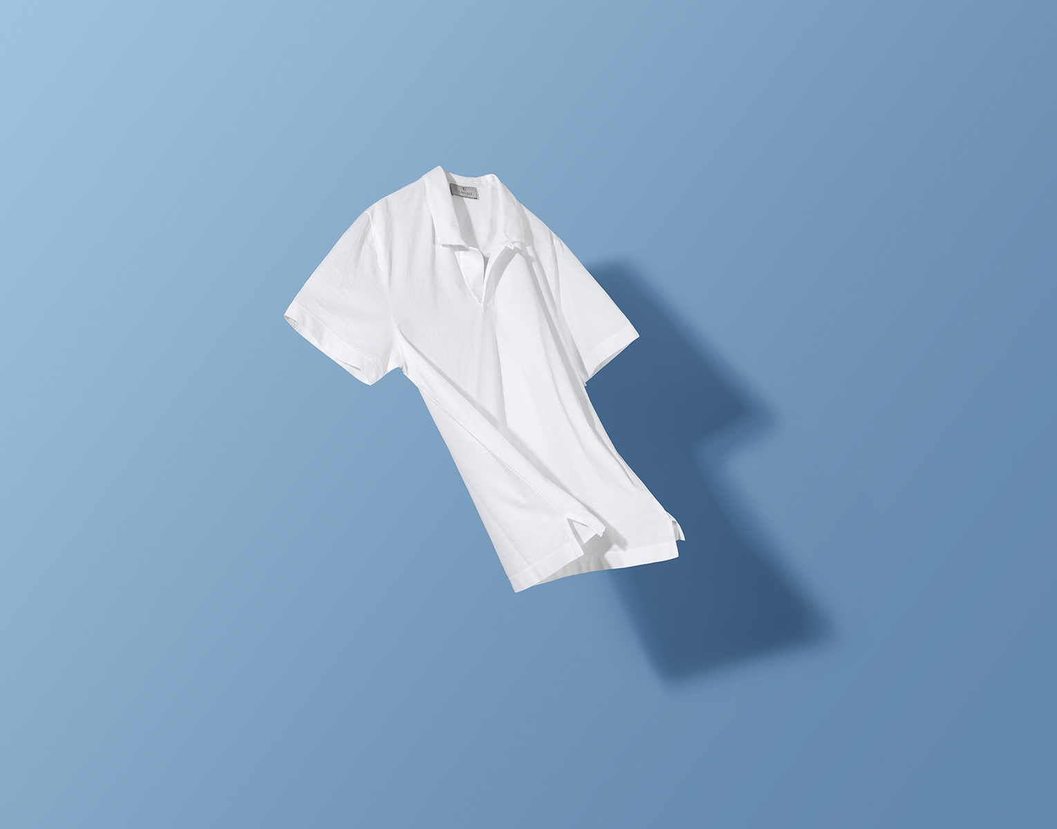 Una polo bianca mossa dal vento davanti ad uno sfondo blu . Campagna Canali social.