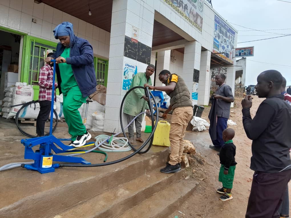 A farmer tests a manual irrigation pump during a demonstration outside a rural supply shop in Rwanda.