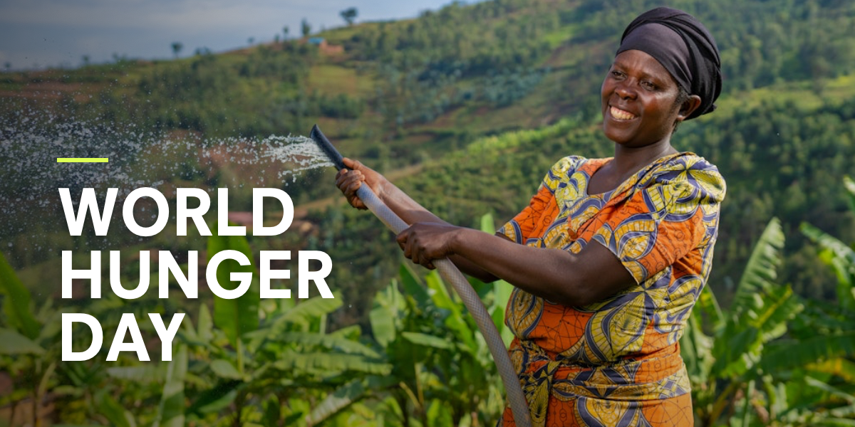 A woman in Rwanda waters her crops with a hose, smiling, with lush green hills in the background. Text reads: World Hunger Day
