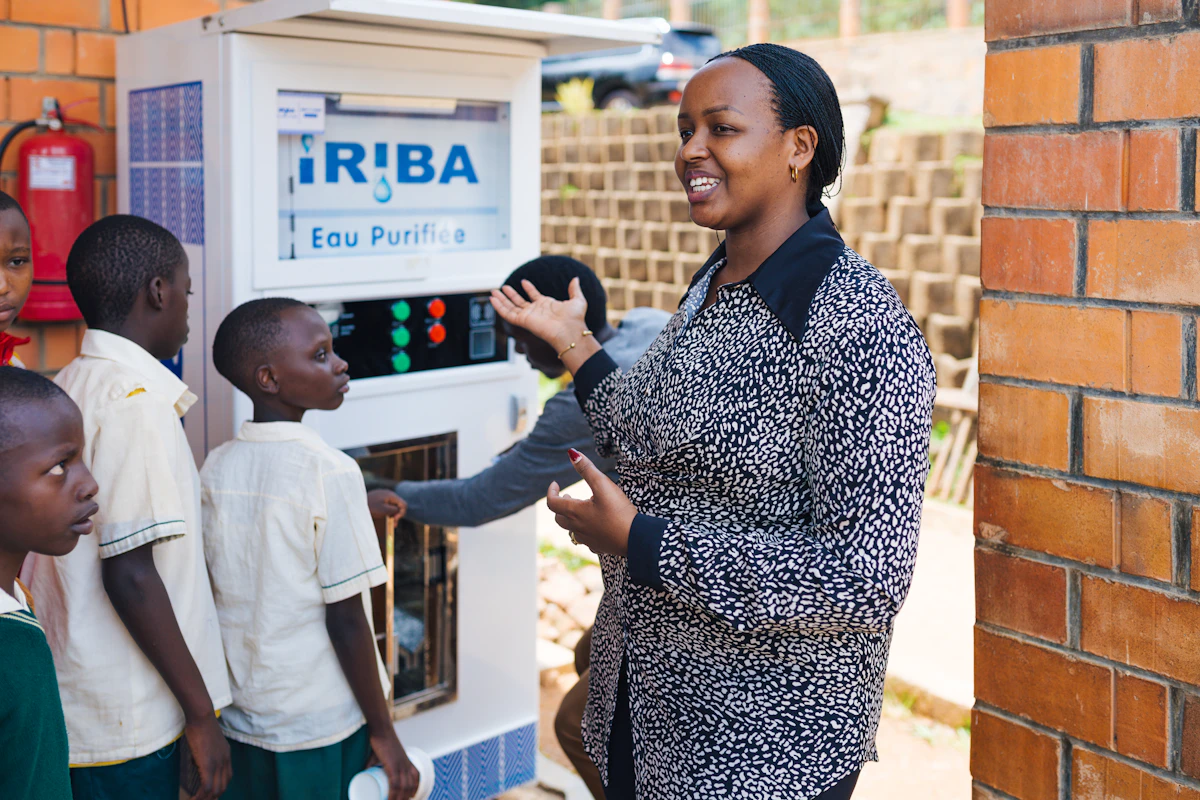 Yvette demonstrates a Tap & Drink Water ATM to students at a school in Rwanda.