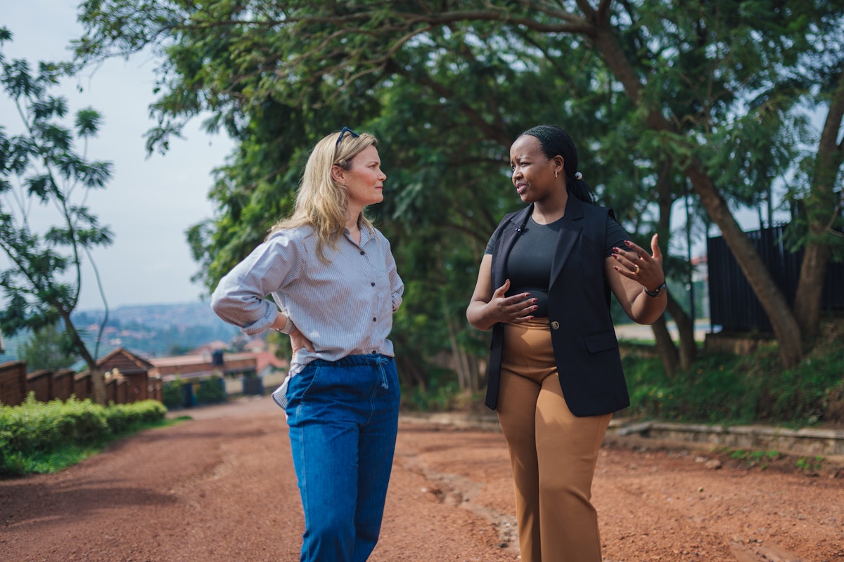 Becky and Yvette are mid-conversation while walking along a dirt road that leads out of a Rwanda village