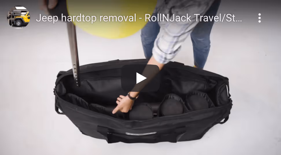 Person arranging tools or equipment inside a large black carrying bag on a white floor.