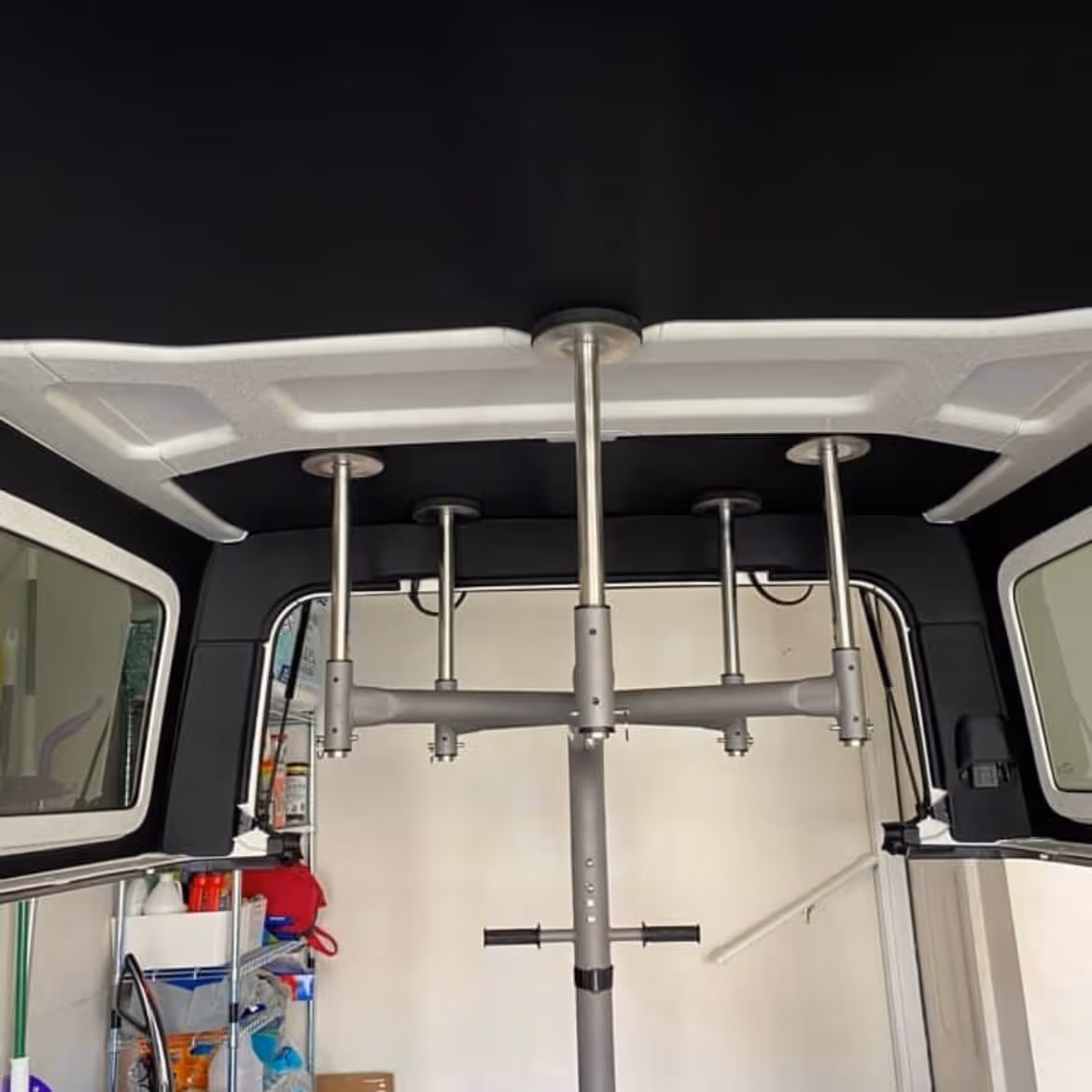 Interior ceiling of a vehicle with a mounted metal fishing rod holder featuring five vertical poles and horizontal arms.